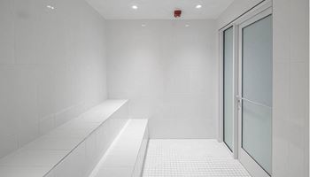 An empty room with white tiles and a glass door